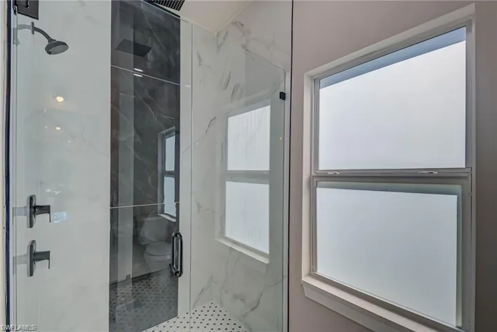 Bathroom with plenty of natural light and a marble finish shower