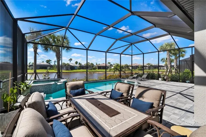 View of pool featuring a lanai, a water view, a patio area, and an in ground hot tub