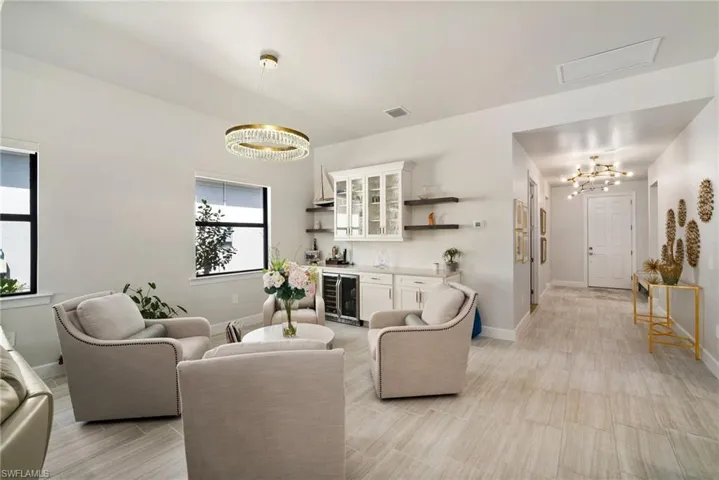 Living room featuring beverage cooler, indoor bar, and a notable chandelier