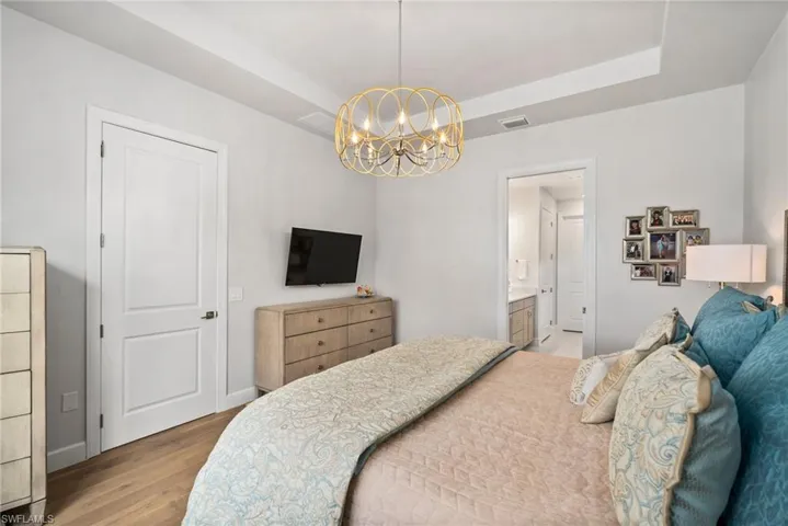 Bedroom featuring light wood-type flooring, an inviting chandelier, and ensuite bathroom
