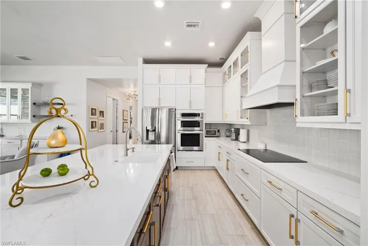 Kitchen with stainless steel appliances, sink, premium range hood, and white cabinets