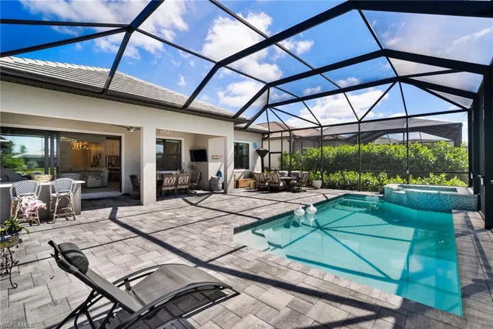 View of swimming pool with glass enclosure, a patio area, and an in ground hot tub