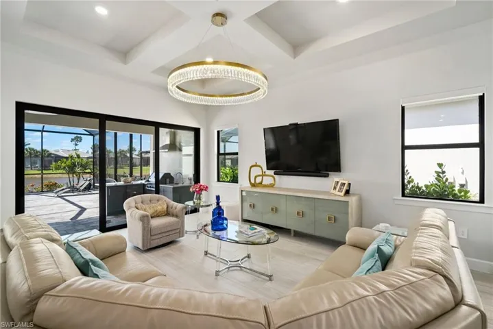 Living room with light wood-type flooring, a tray ceiling, and a notable chandelier