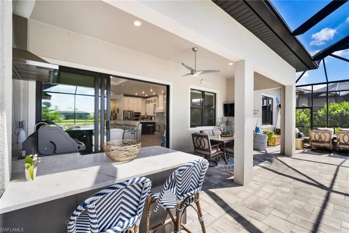 View of patio / terrace with exterior bar, exterior kitchen, glass enclosure, and ceiling fan