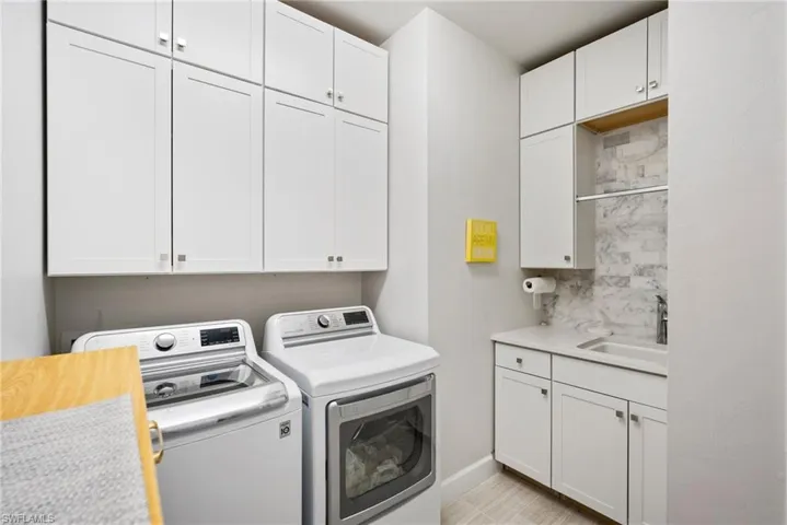 Laundry area featuring separate washer and dryer, cabinets, and sink