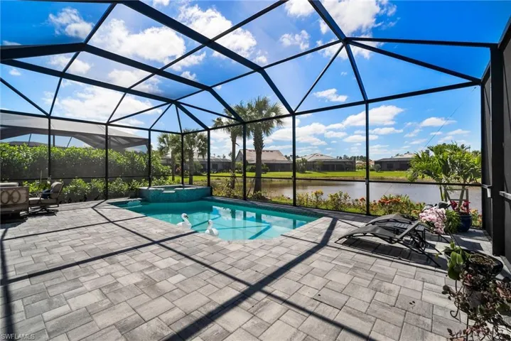 View of pool featuring a water view, a lanai, a patio, and an in ground hot tub
