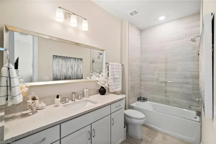 Full bathroom with tiled shower / bath, toilet, hardwood / wood-style flooring, and vanity