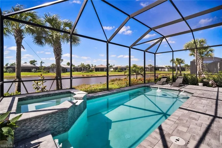 View of pool with glass enclosure, a water view, and a patio