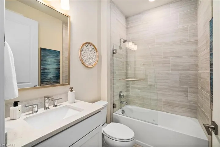 Full bathroom with toilet, tiled shower / bath combo, and vanity