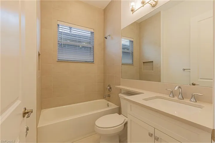 Full bathroom with tile flooring, vanity, toilet, and tiled shower / bath combo