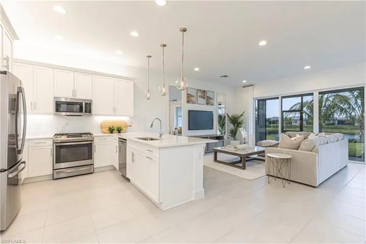 Kitchen with kitchen peninsula, light tile flooring, hanging light fixtures, sink, and appliances with stainless steel finishes