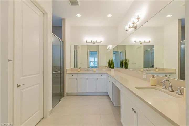 Bathroom with tile flooring, an enclosed shower, double sink, and large vanity