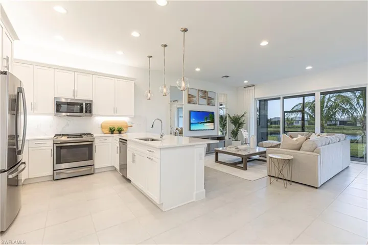 Kitchen featuring kitchen peninsula, stainless steel appliances, decorative light fixtures, light tile floors, and sink