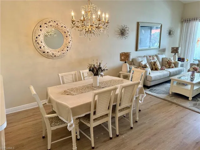 Dining space with wood finished floors, a chandelier, and baseboards