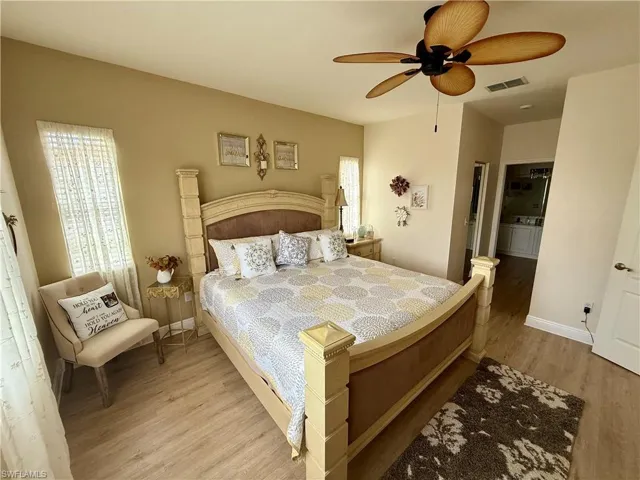 Bedroom with wood finished floors, multiple windows, a ceiling fan, and baseboards