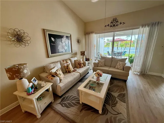 Living room featuring wood finished floors, lofted ceiling, and baseboards