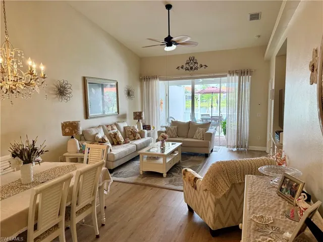 Living area featuring ceiling fan, wood finished floors, a chandelier, and vaulted ceiling