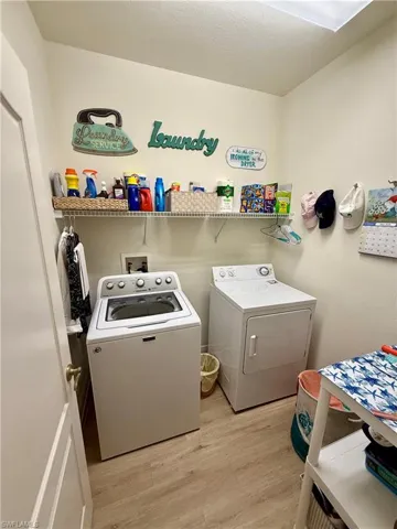Washroom with washing machine and dryer and wood finished floors