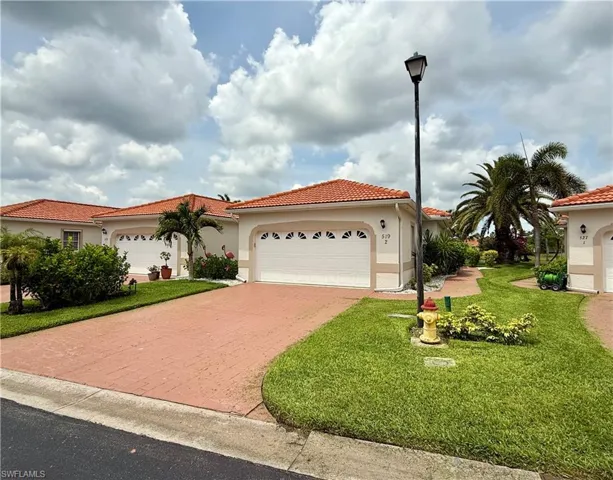 Mediterranean / spanish-style house with a garage, decorative driveway, a front lawn, and a tile roof