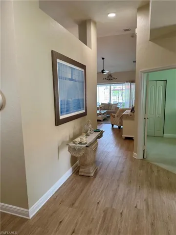 Hallway featuring baseboards, wood finished floors, and high vaulted ceiling