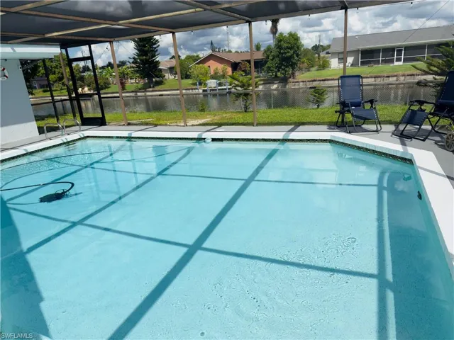 Swimming pool featuring glass enclosure, a water view, a sunroom, and a patio