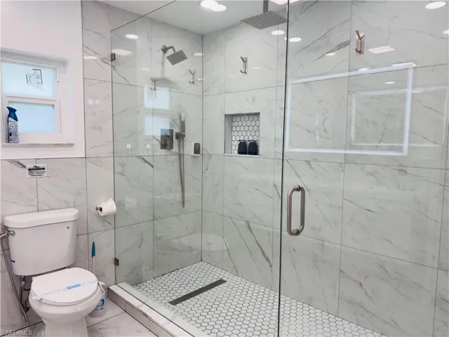 Full bathroom with a marble finish shower and tile walls