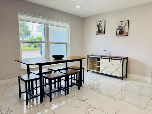 Dining room with light marble finish floors and recessed lighting