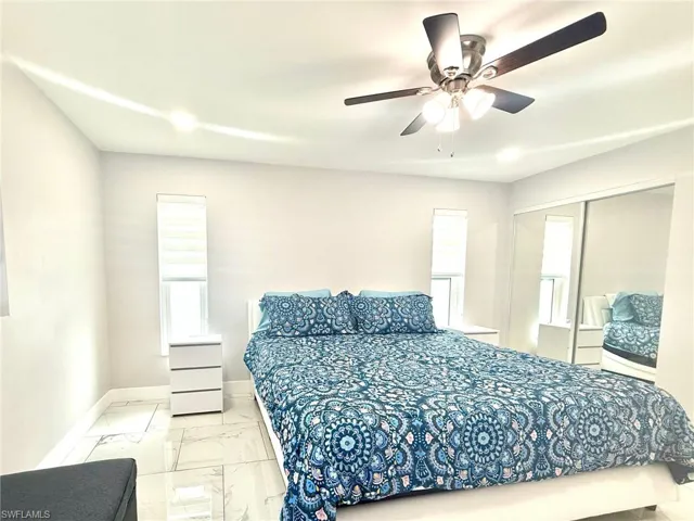 Bedroom with light marble finish flooring, a ceiling fan, a closet, and recessed lighting