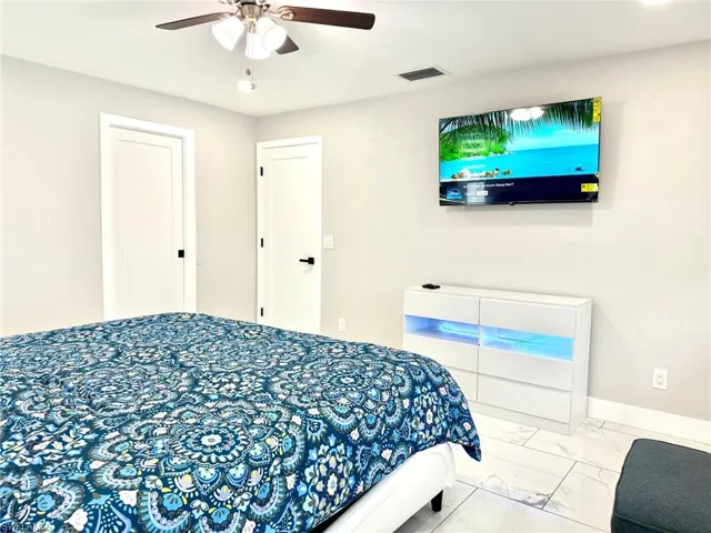 Bedroom featuring marble look tiles and a ceiling fan