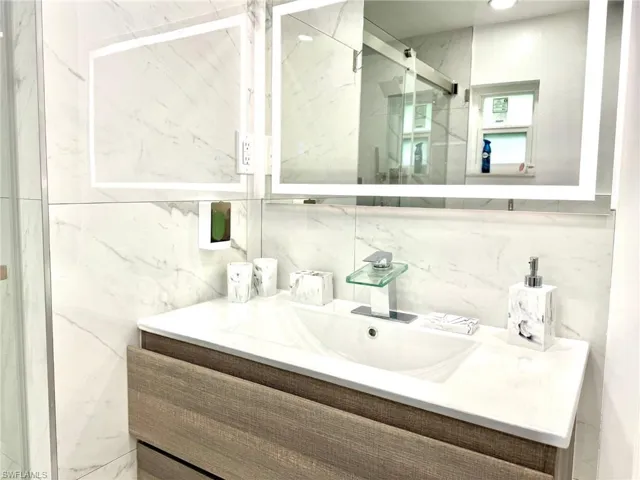 Bathroom with vanity and a marble finish shower