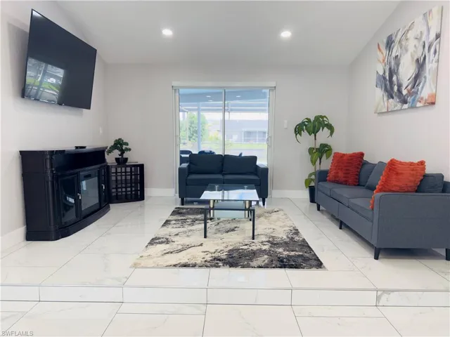 Living area featuring light marble finish floors, recessed lighting, and a glass covered fireplace