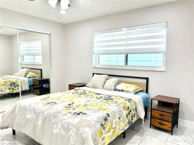 Bedroom with a closet, light marble finish flooring, multiple windows, and ceiling fan
