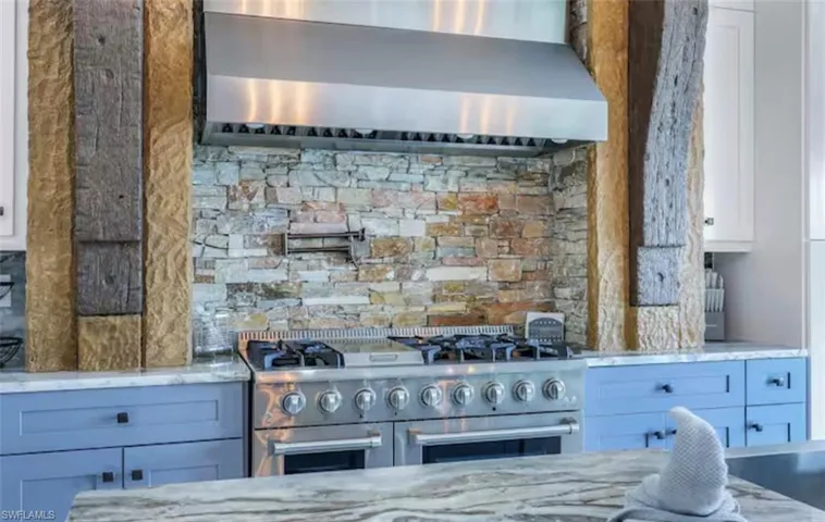 Kitchen with light stone countertops, double oven range, and white cabinets