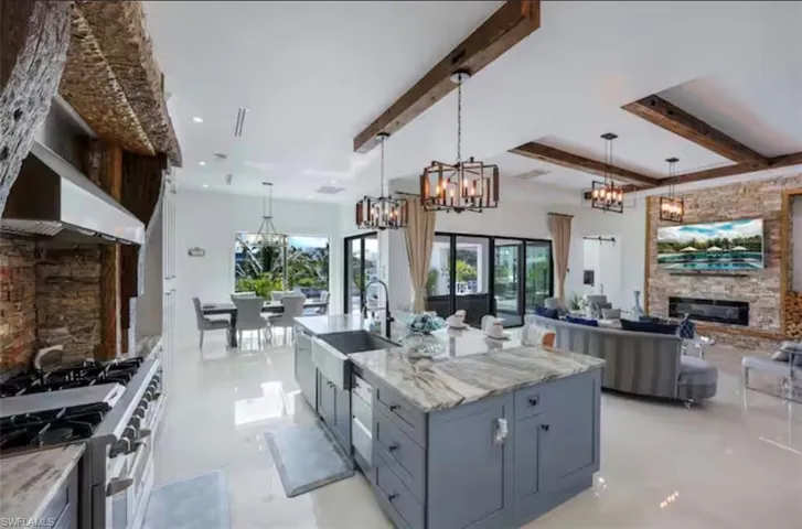 Kitchen with a fireplace, double oven range, light stone counters, open floor plan, and hanging lights