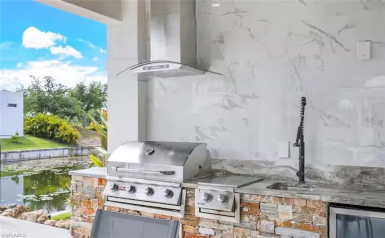 View of patio with an outdoor kitchen and a water view