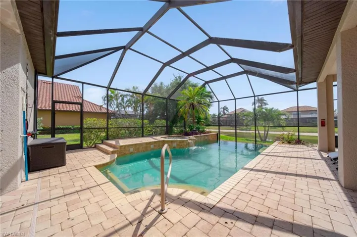View of pool with a pool with connected hot tub, glass enclosure, and a patio area