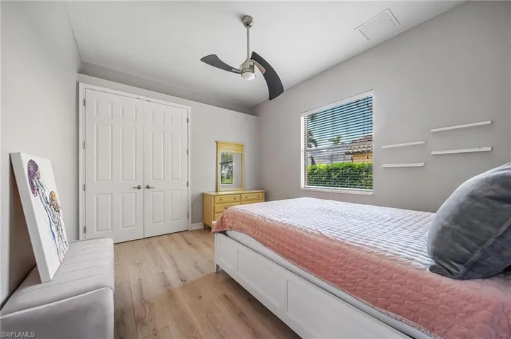 Bedroom with ceiling fan, light wood-type flooring, visible vents, and a closet
