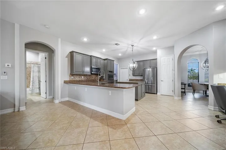 Kitchen featuring gray cabinetry, stainless steel appliances, a peninsula, and arched walkways
