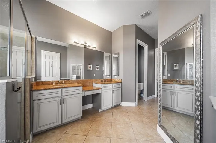 Full bath featuring tile patterned floors, visible vents, two vanities, and a sink