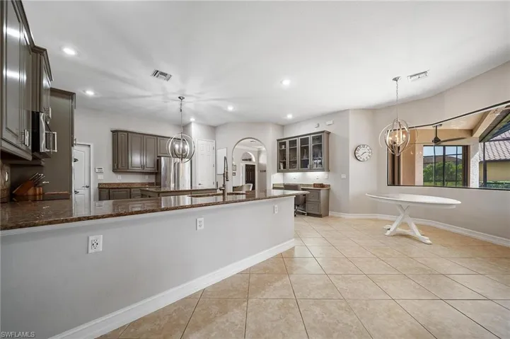 Kitchen with a sink, dark stone countertops, an inviting chandelier, and visible vents