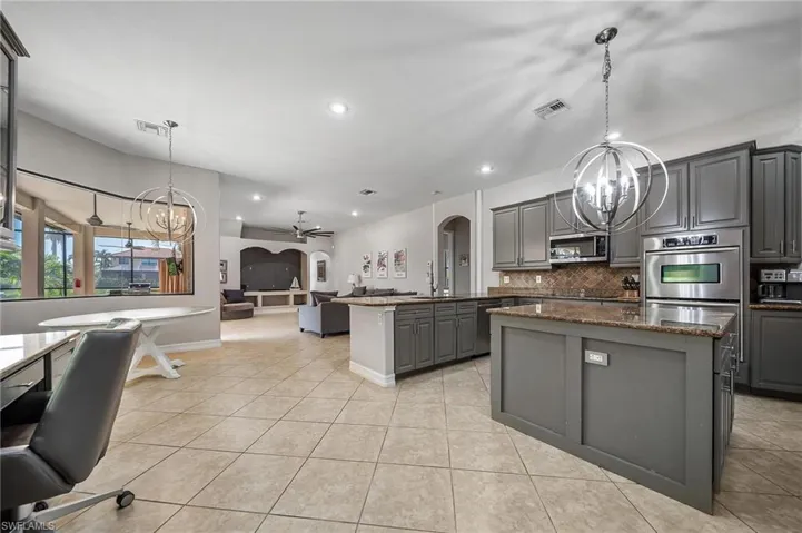 Kitchen with stainless steel appliances, gray cabinets, a center island, visible vents, and open floor plan