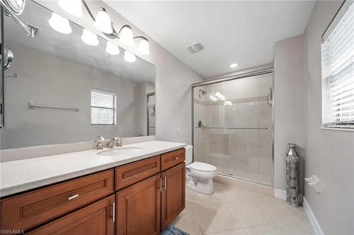 Full bathroom featuring vanity, toilet, a stall shower, visible vents, and tile patterned flooring
