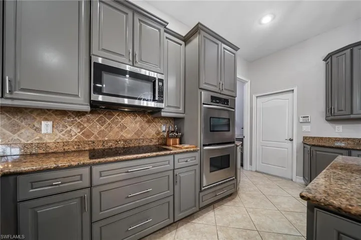 Kitchen with tasteful backsplash, gray cabinets, recessed lighting, stainless steel appliances, and light tile patterned flooring