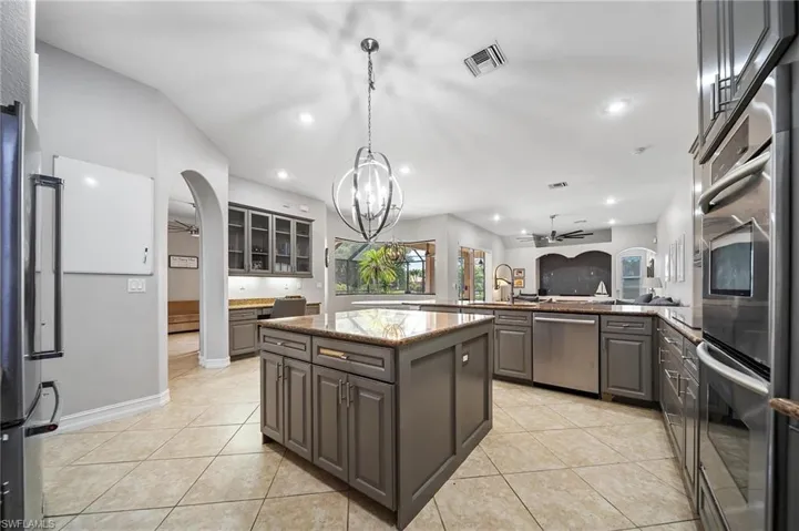 Kitchen with appliances with stainless steel finishes, visible vents, gray cabinets, arched walkways, and ceiling fan with notable chandelier