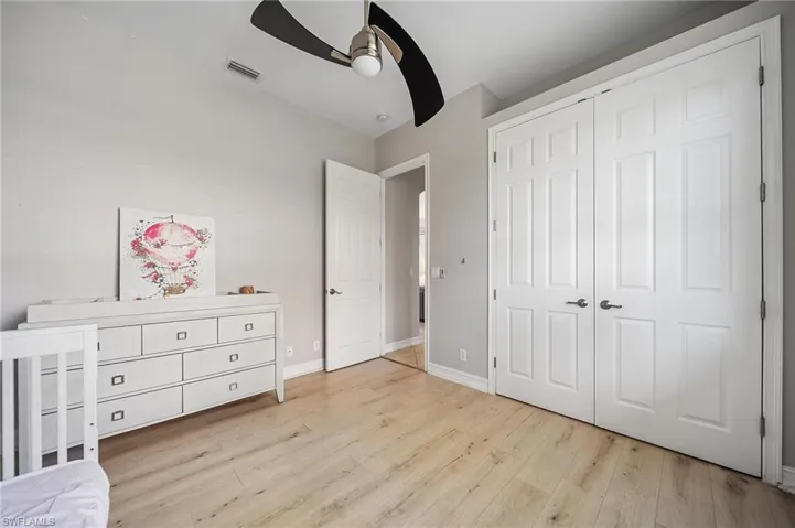 Bedroom with visible vents, ceiling fan, a closet, baseboards, and wood finished floors