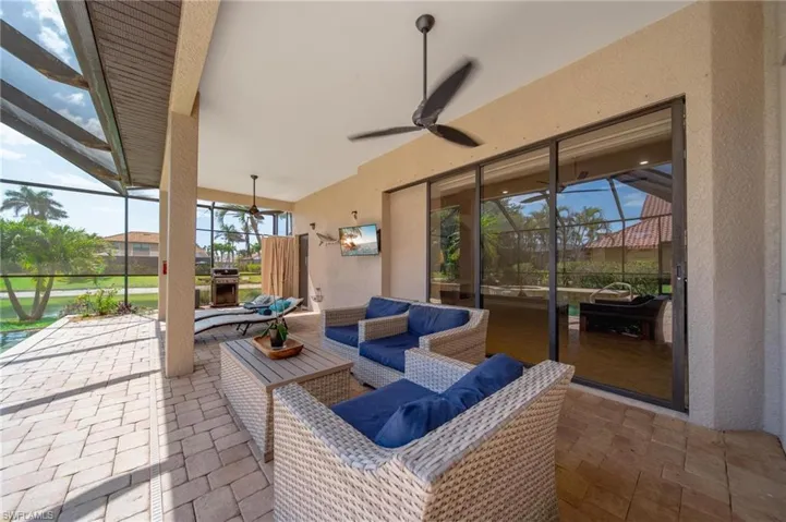 View of patio featuring a ceiling fan, outdoor lounge area, and glass enclosure