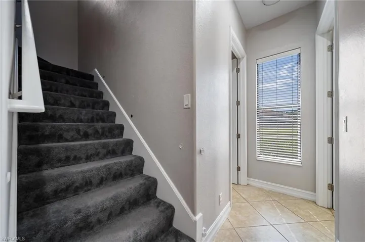 Stairway with tile patterned floors and baseboards