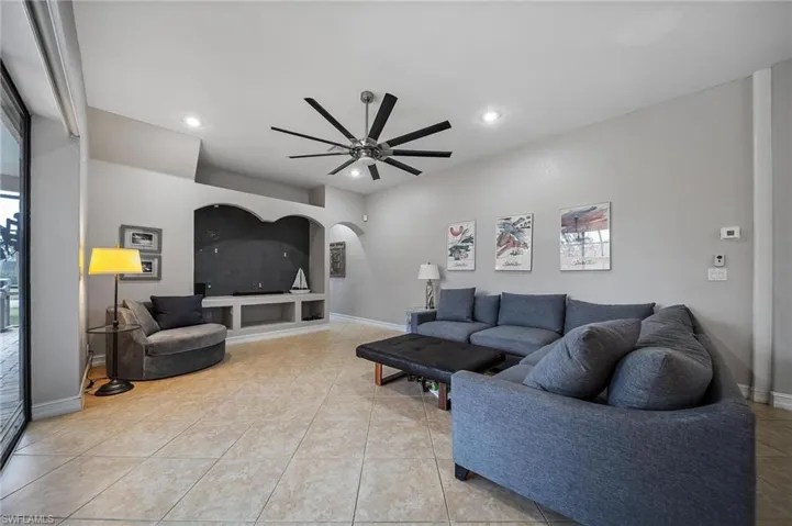 Living area featuring recessed lighting, light tile patterned flooring, ceiling fan, baseboards, and arched walkways
