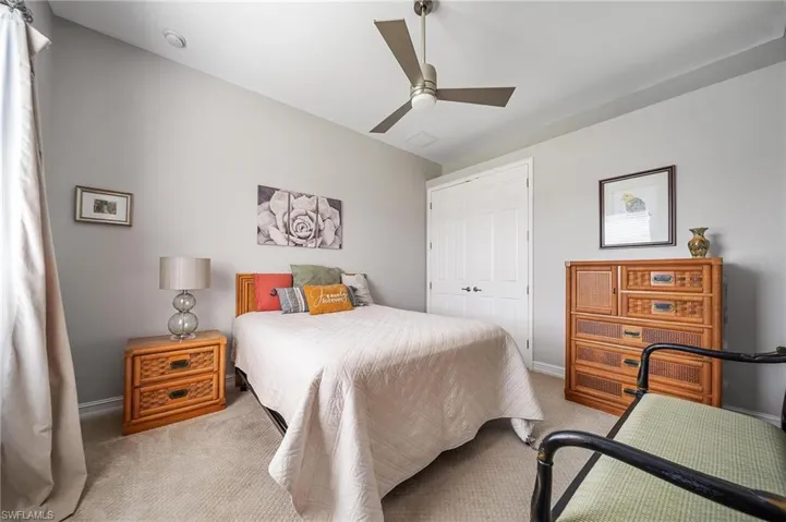 Carpeted bedroom featuring baseboards, a ceiling fan, and a closet