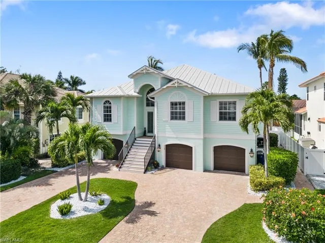 Coastal inspired home featuring a standing seam roof, an attached garage, and decorative driveway